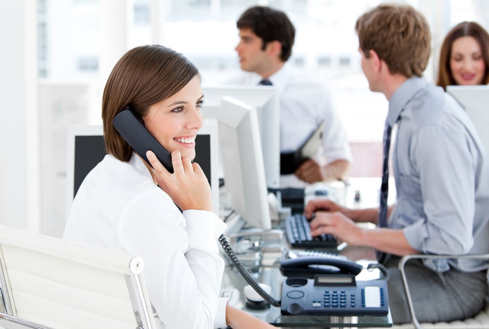 Enthousiastic businesswoman talking to the phone in the open-space